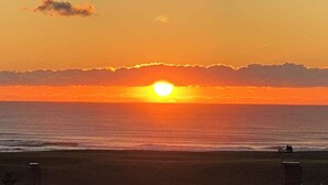 Un atardecer sobre el océano, con una playa al frente.