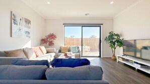 A modern living room with a grey sofa, a coffee table, and a TV on a stand.