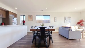 A modern kitchen with a dining area, a sofa, and a window with a view.