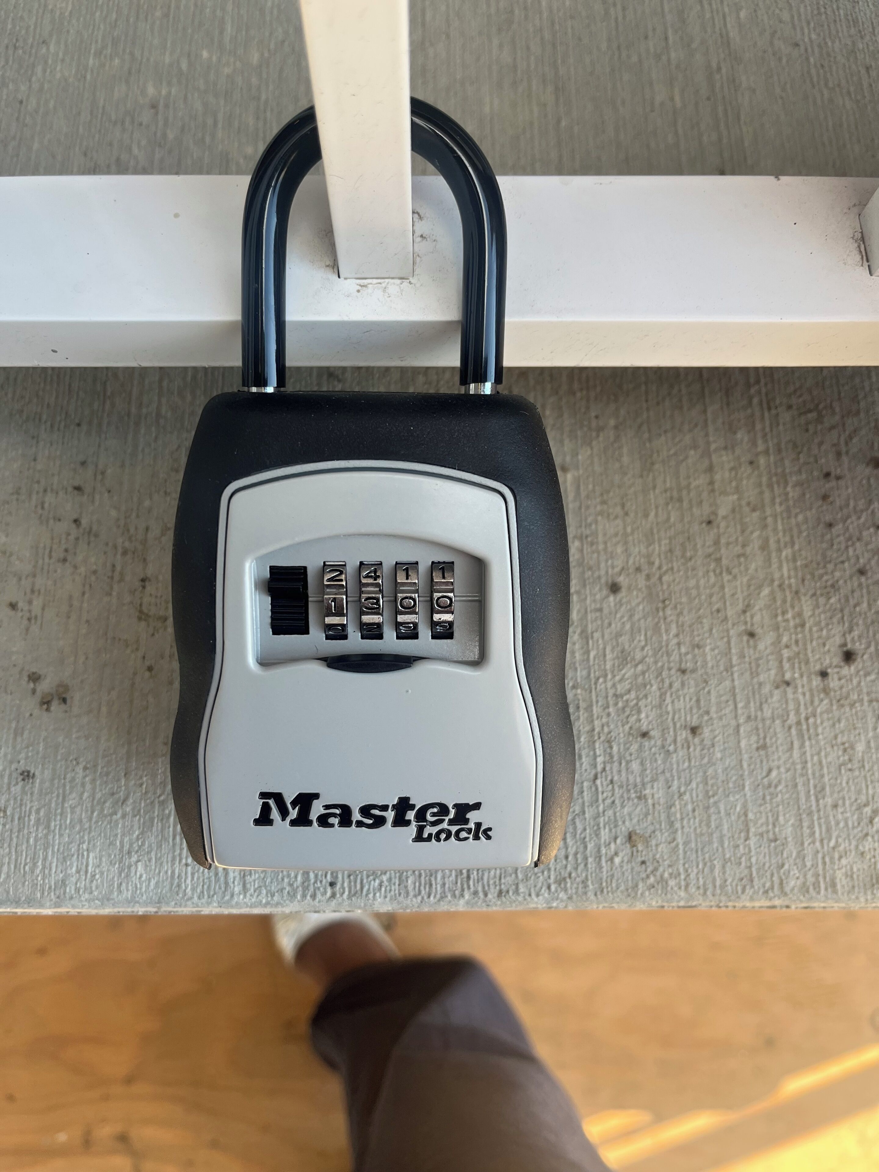 Un candado Master Lock sujeto a una barra de metal blanco.