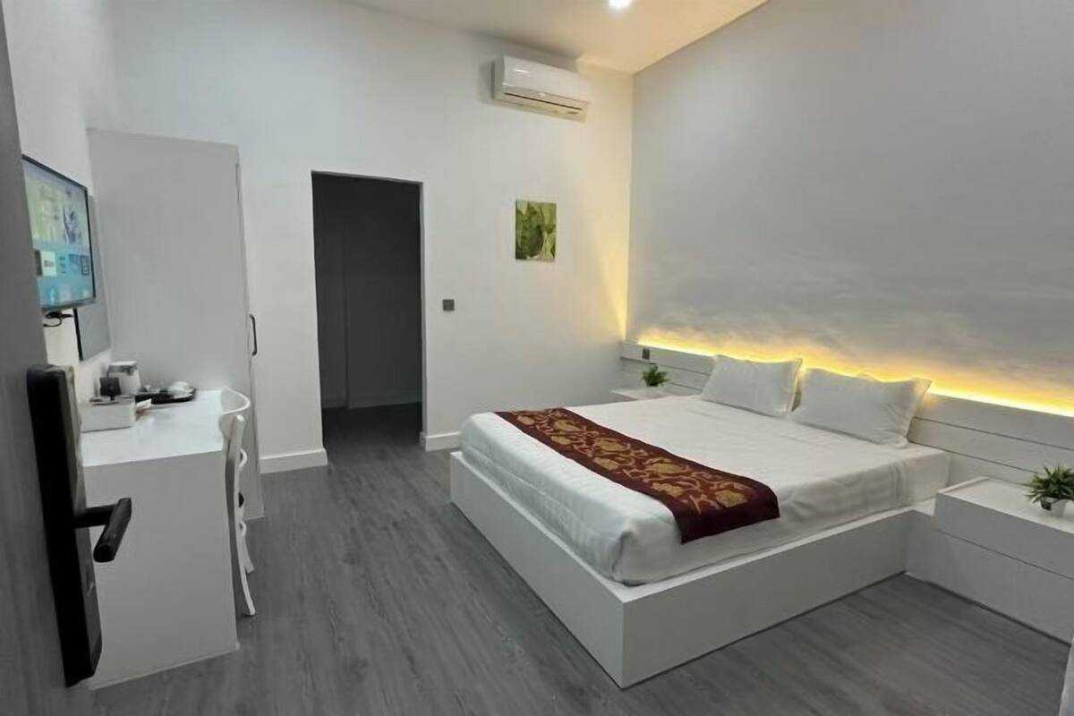 A modern bedroom with a bed, bedside tables, a desk, and a chair.