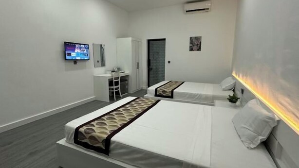 A hotel room with two beds, a desk, a chair, a TV, and a wardrobe. - The Aura Residence (Sihanoukville)