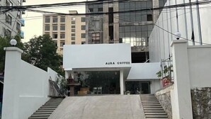 A building with a sign reading "AURA COFFEE" at the entrance, featuring a staircase leading up to the door. - The Aura Residence (Sihanoukville)