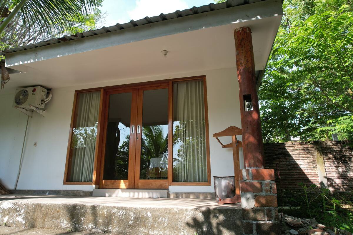 A house with a large sliding glass door, a small porch, and a brick column.