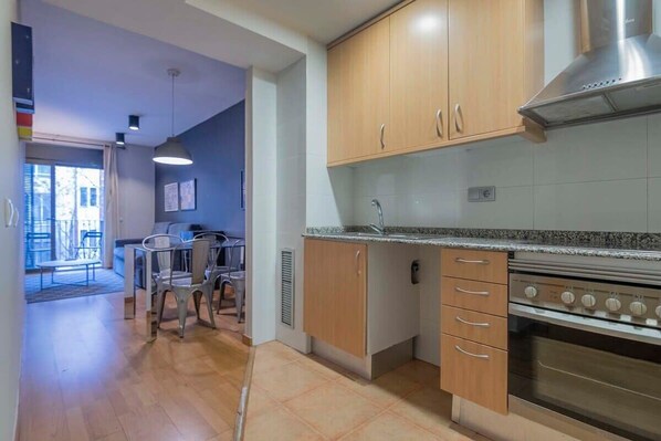 Una cocina con armarios de madera, una campana extractora de acero inoxidable y un horno empotrado.