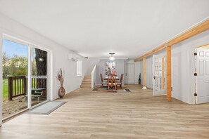 A spacious hallway with a wooden floor, a dining area with a table and chairs, and a staircase leading to another level. - Cedar Creek Escape: Spacious 4 Bedroom Chateau,  Private Pond & Creek Frontage (Amboy)