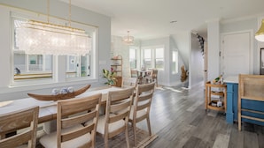 Une salle à manger spacieuse avec une grande fenêtre, des chaises en bois et un lustre.