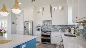 Une cuisine moderne avec des armoires blanches, des appareils en acier inoxydable et un mur d’accent bleu.