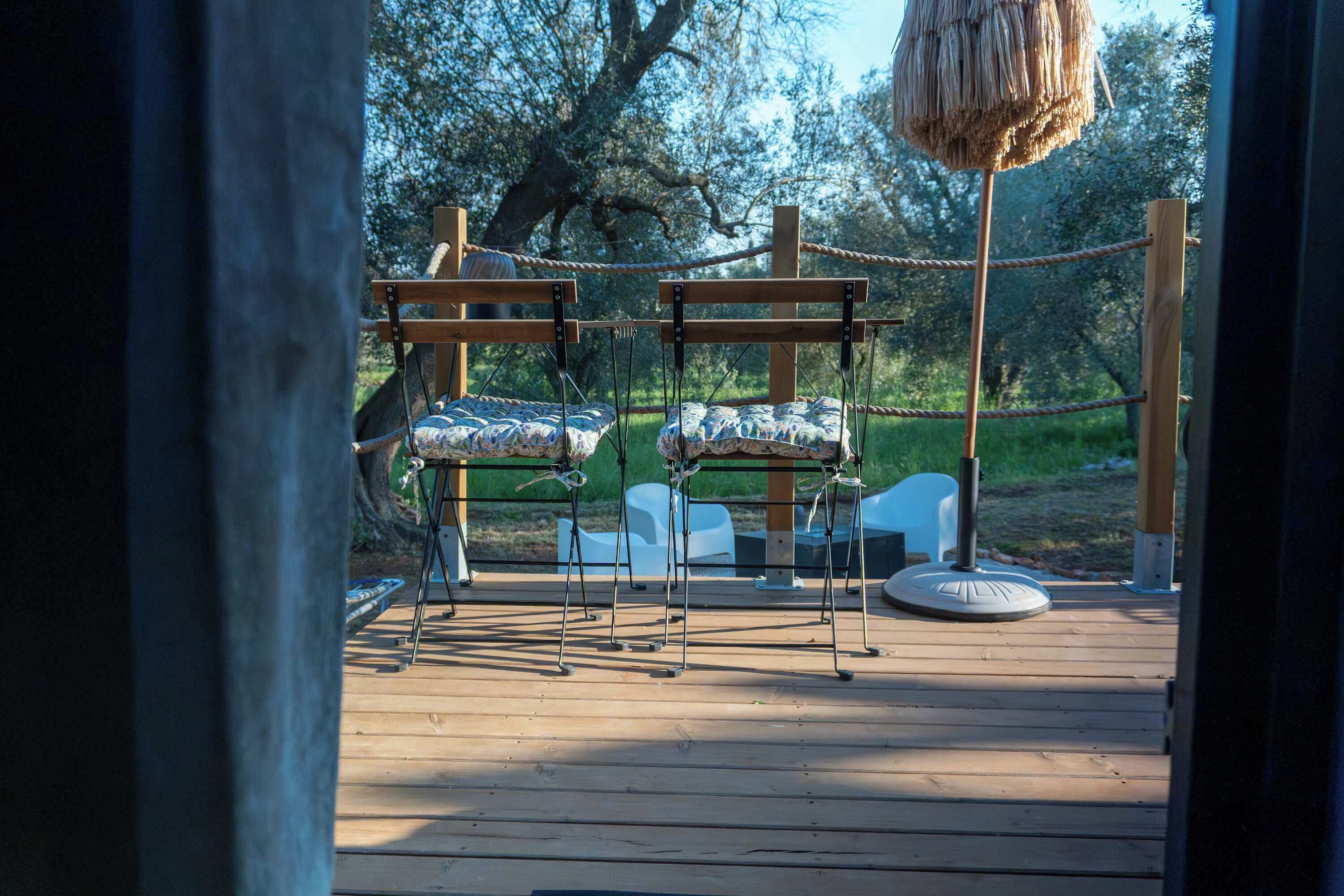 A wooden deck with two swing seats and a hanging basket.