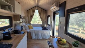 Ein gemütlicher Raum mit einem Bett, einem kleinen Tisch mit Früchten, einer Mikrowelle und einem Fenster mit Vorhängen.