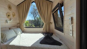 Ein gemütliches Zimmer mit einem Bett, einem Vorhangfenster, einem Kleiderständer und einem Wandheizk örper.