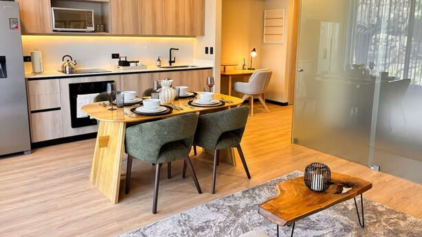Una cocina moderna con armarios de madera, un microondas y un comedor con mesa y sillas.