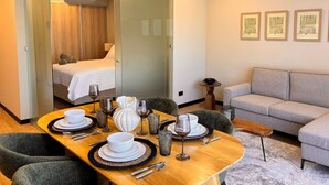 Una habitación de hotel moderna con comedor, sofá y cama.