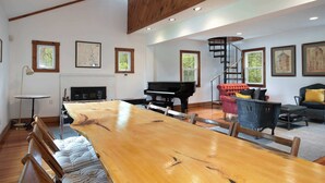 Une pièce spacieuse avec une grande table à manger en bois, un magnifique piano à queue et des sièges confortables.
