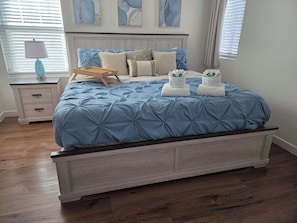 A bedroom with a bed, bedside tables, a lamp, and artwork on the wall.
