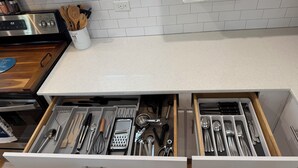 A kitchen with white cabinets, a countertop, and a drawer with kitchen utensils. - Lux Midtown; Mins to Uptown, Biltmore, Melrose District, Papago Park, & Sports (Phoenix)