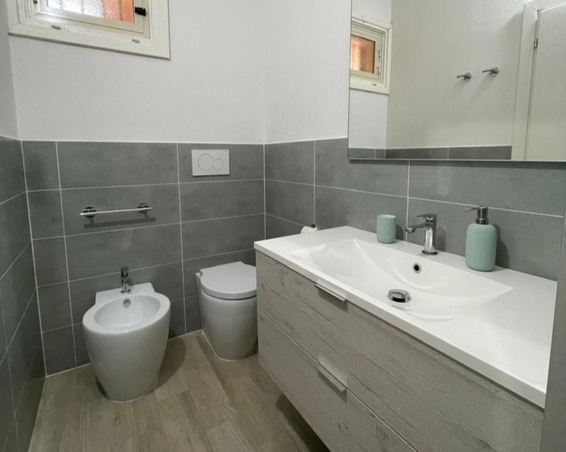 Ein Badezimmer mit einer Bidet-Funktion, Toilette und einem Waschtisch mit Waschbecken und Spiegel.