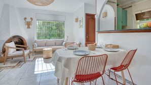 A dining area with a table set for four, surrounded by wicker chairs and a sofa.