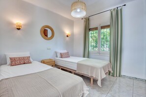 A room with two beds, a round mirror, and a window with curtains. - ESCALE: Beautiful holiday rental house with private pool in Masos de Pals (Pals)