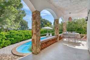 A covered outdoor area with a pool, stone pillars, and a table with chairs. - ESCALE: Beautiful holiday rental house with private pool in Masos de Pals (Pals)