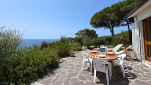Une terrasse avec une table dressée pour le repas, offrant une vue panoramique sur la mer.