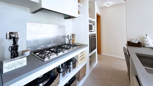 Une cuisine moderne équipée d’une cuisinière à gaz, d’un four et d’un four à micro-ondes. On y trouve des placards et un luminaire suspendu.