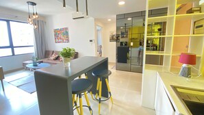 Una cocina moderna con una isla central, detalles en color amarillo y una zona de comedor con taburetes.