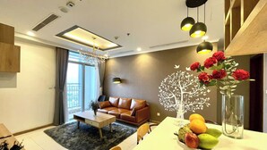 Una sala de estar moderna con un sofá de cuero marrón, una mesa de comedor con fruta y un jarrón de flores.