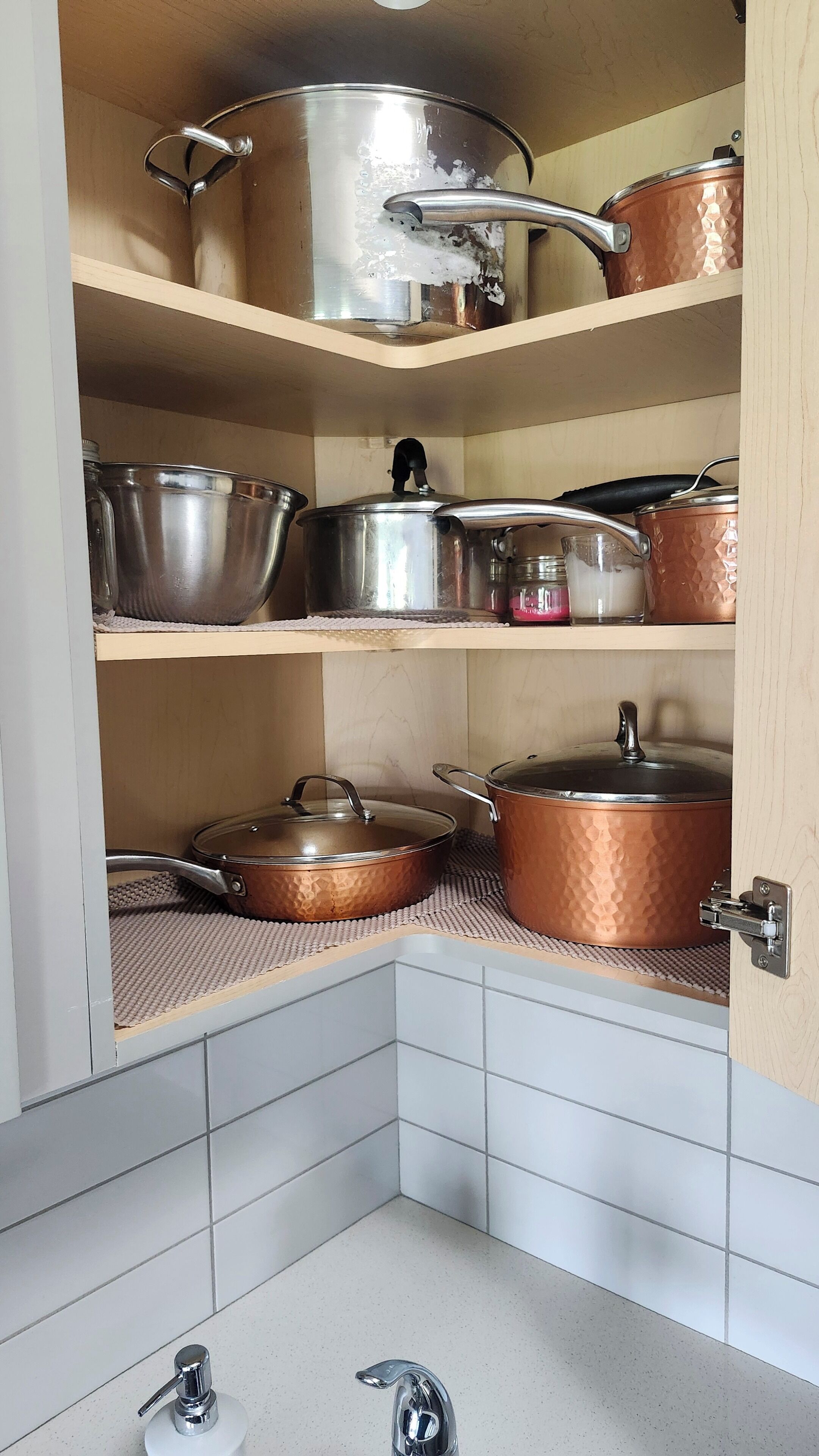Een keuken met drie planken waarop diverse pannen en braadpannen staan.