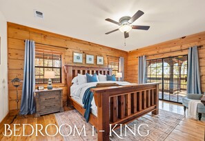 A bedroom with a wooden bed, a ceiling fan, and a view through a glass door. - NorthWing Bear Resort | Adventure-Ready Escape (Broken Bow)