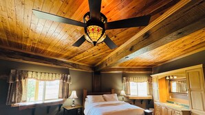Une chambre à coucher avec un plafond en bois, un lit, une table de chevet, une commode et une fenêtre avec des rideaux.