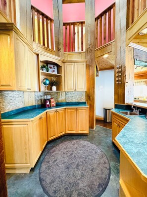 A spacious kitchen with wooden cabinets, a granite countertop, and a central island. - Octagon Oasis | Private Indoor Pool & Lake Access (Bonnyville)