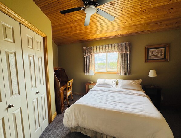A bedroom with a bed, a desk, a chair, a ceiling fan, and a window with curtains. - Octagon Oasis | Private Indoor Pool & Lake Access (Bonnyville)
