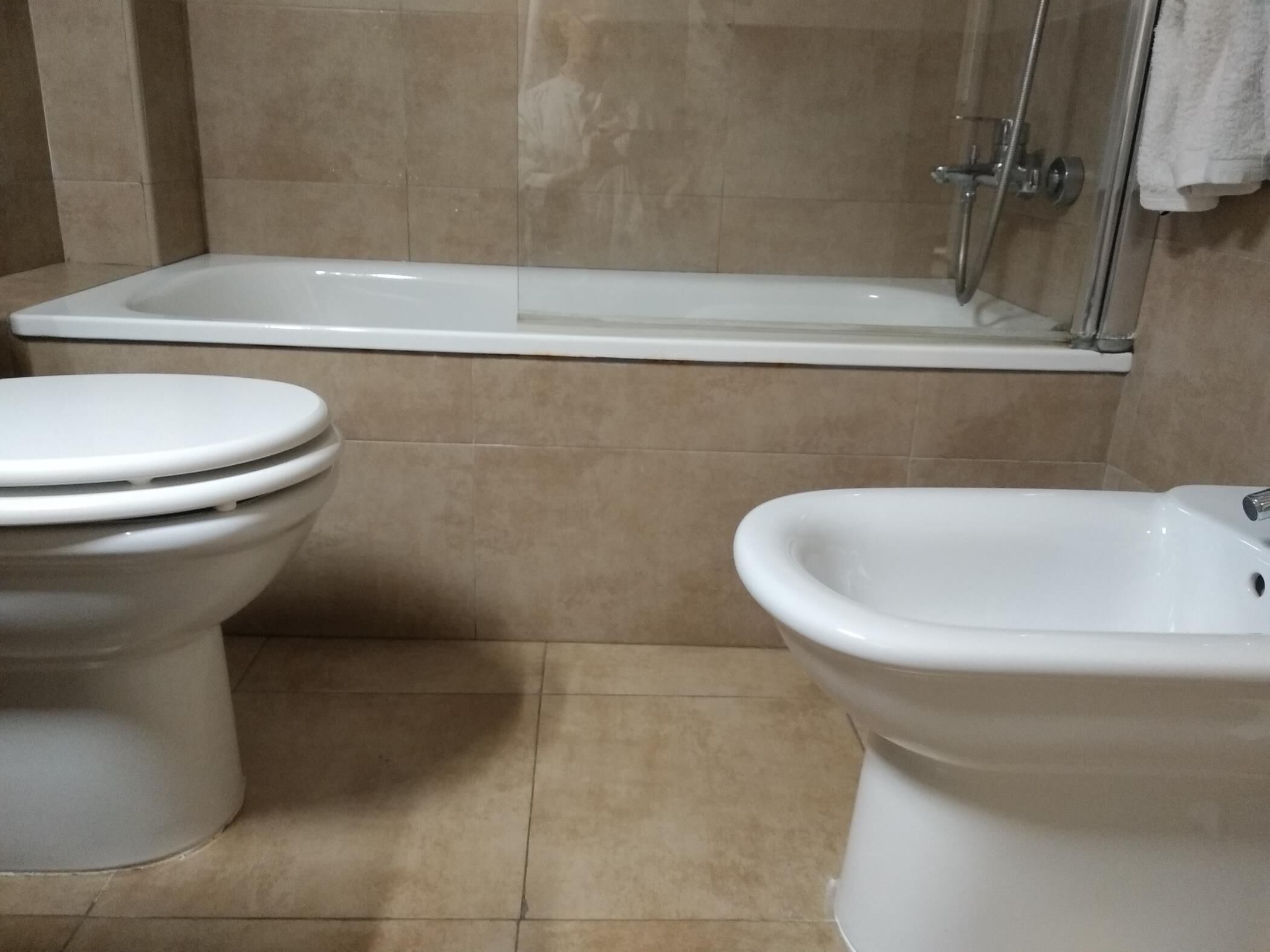 Een badkamer met toilet, bidet en bad.