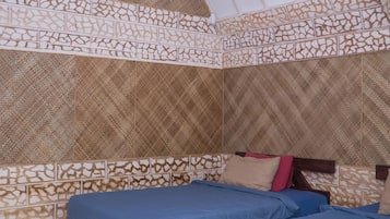 Quarto com duas camas de madeira, paredes estampadas e um aparelho de ar condicionado.