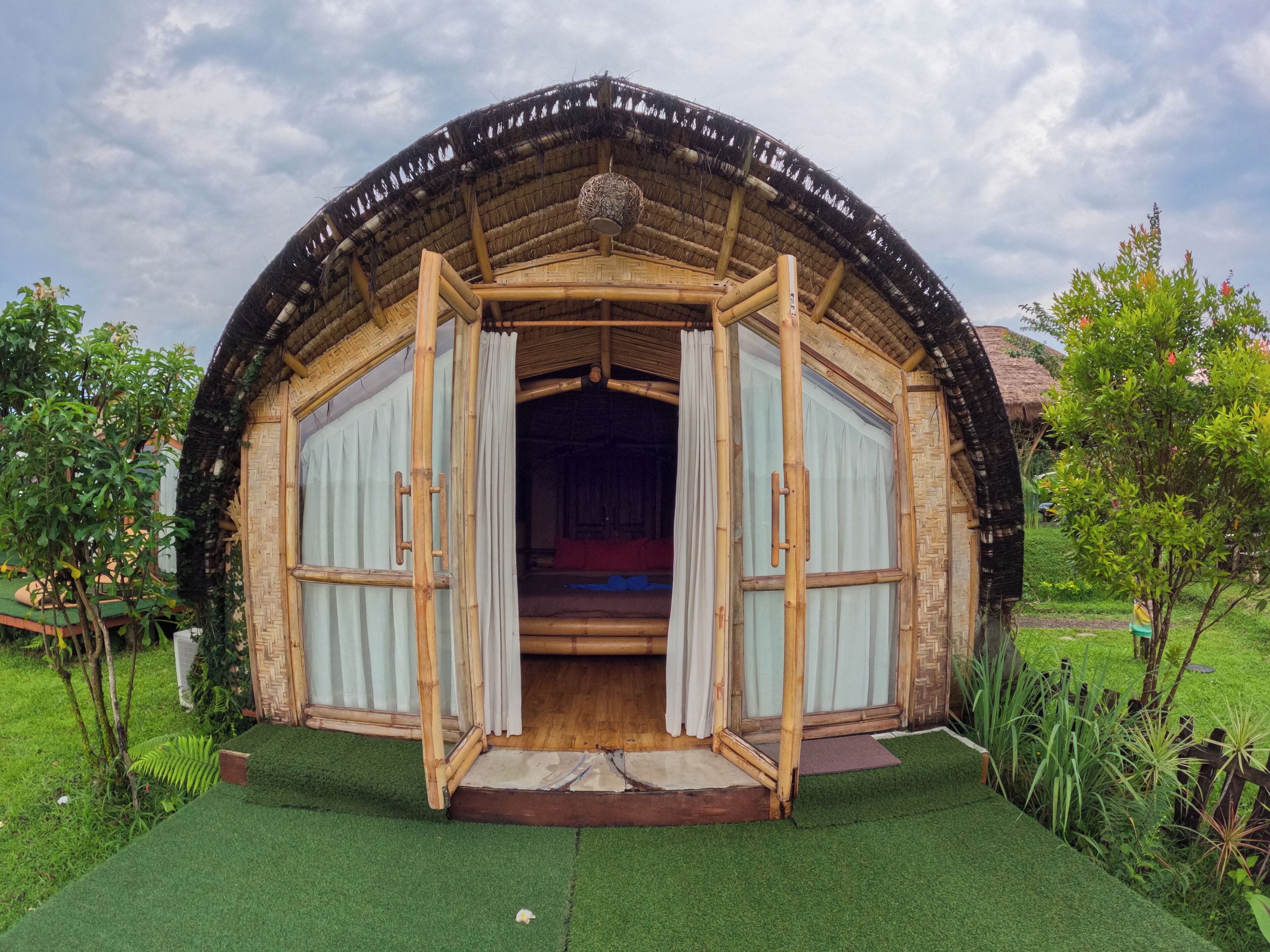 A thatched-roof, circular structure with an open entrance, surrounded by greenery.