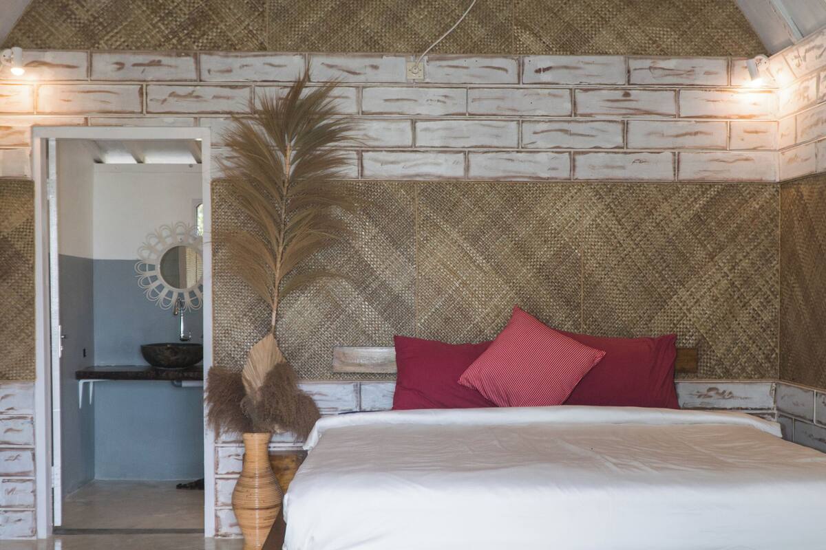 Une chambre avec un lit en bois, une tête de lit en osier et un tapis rond.