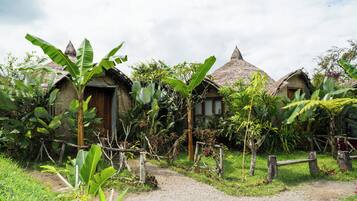 Un village rural aux maisons aux toits de chaume, entouré d’une végétation luxuriante.