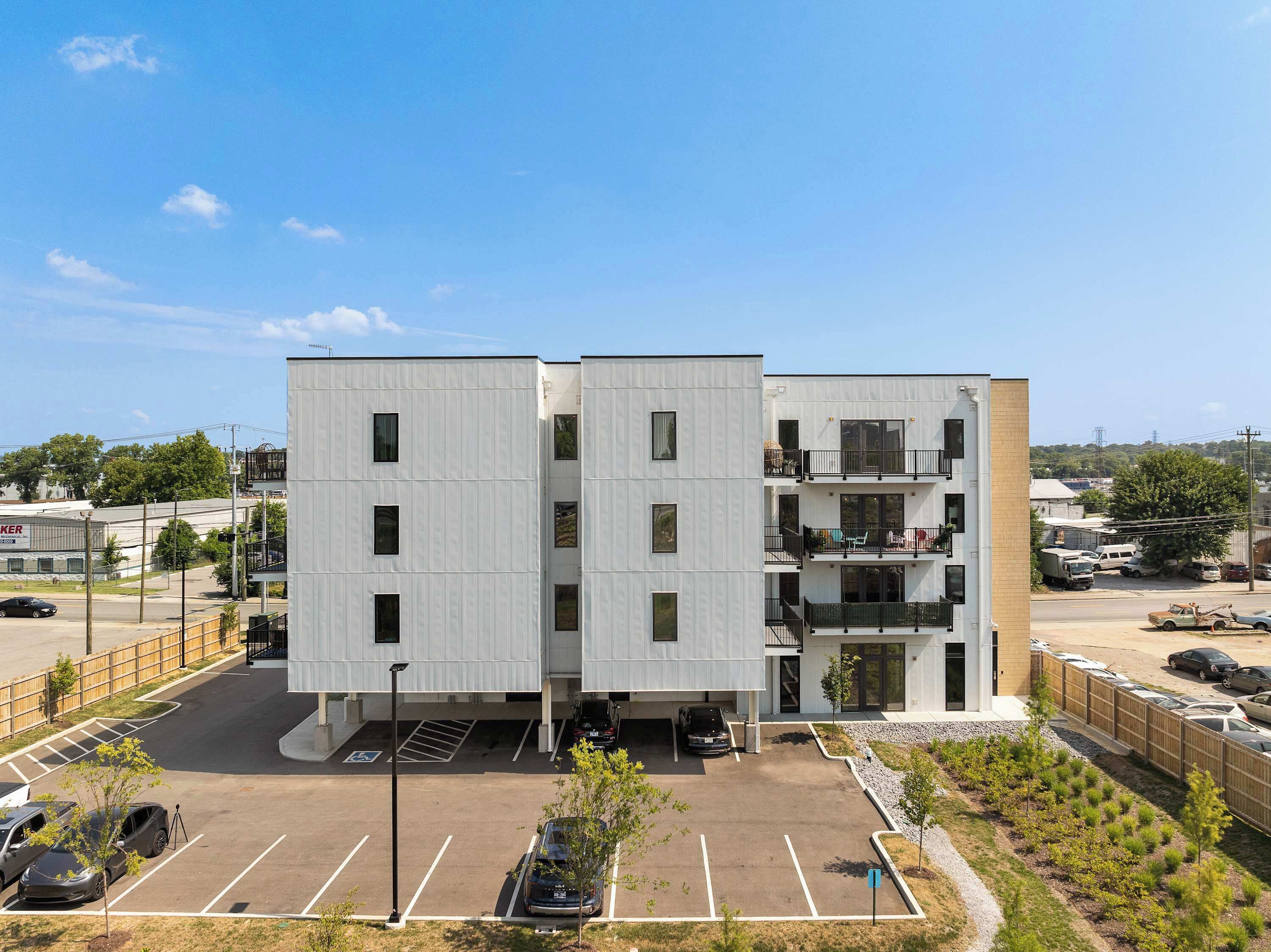 A modern multi-story building with a parking lot in front.