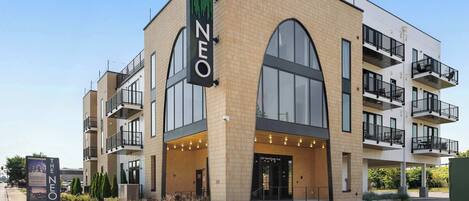 A modern multi-story building with a prominent "NEO" sign, large windows, and balconies.