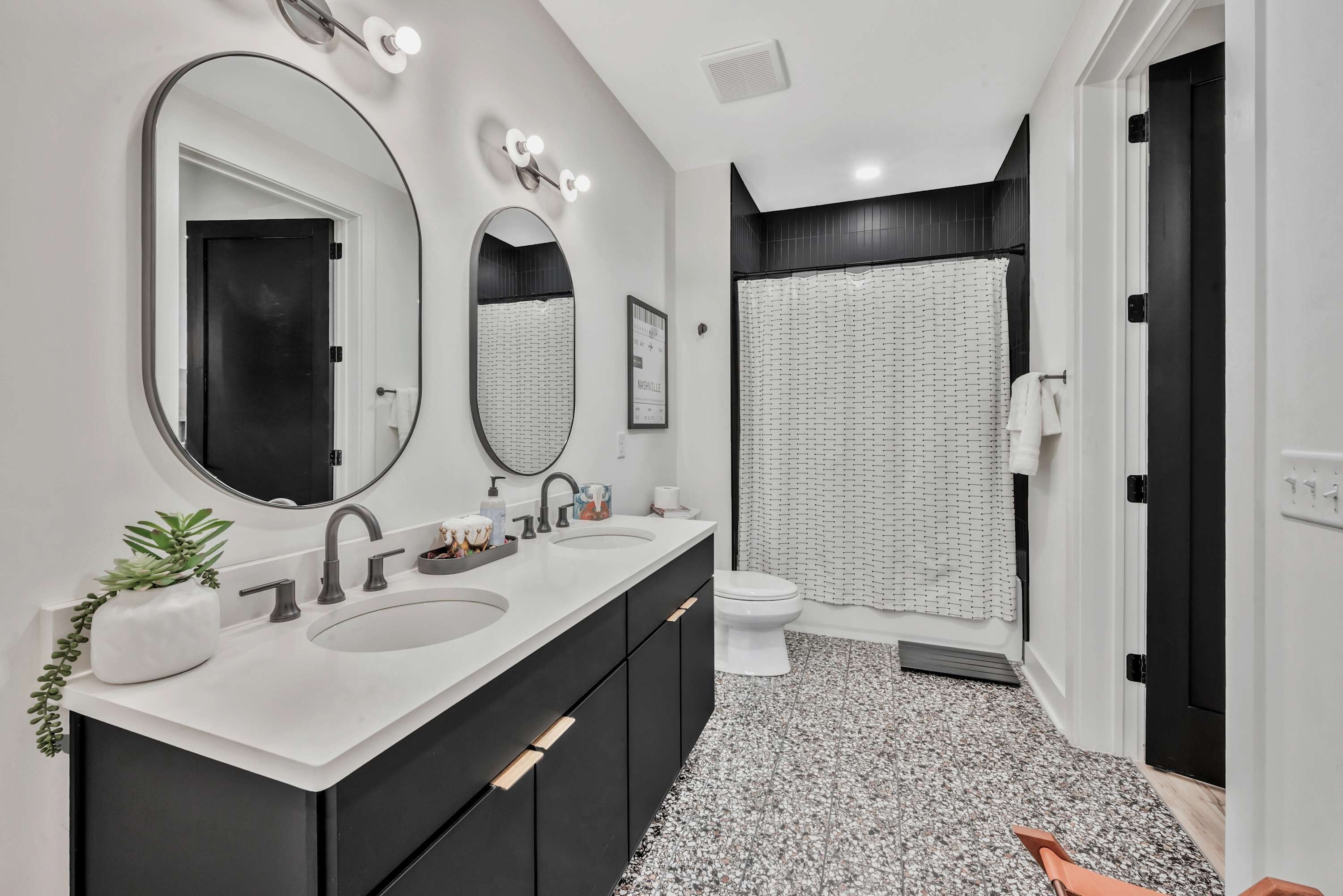 A modern bathroom with two sinks, a large mirror, and a shower area.