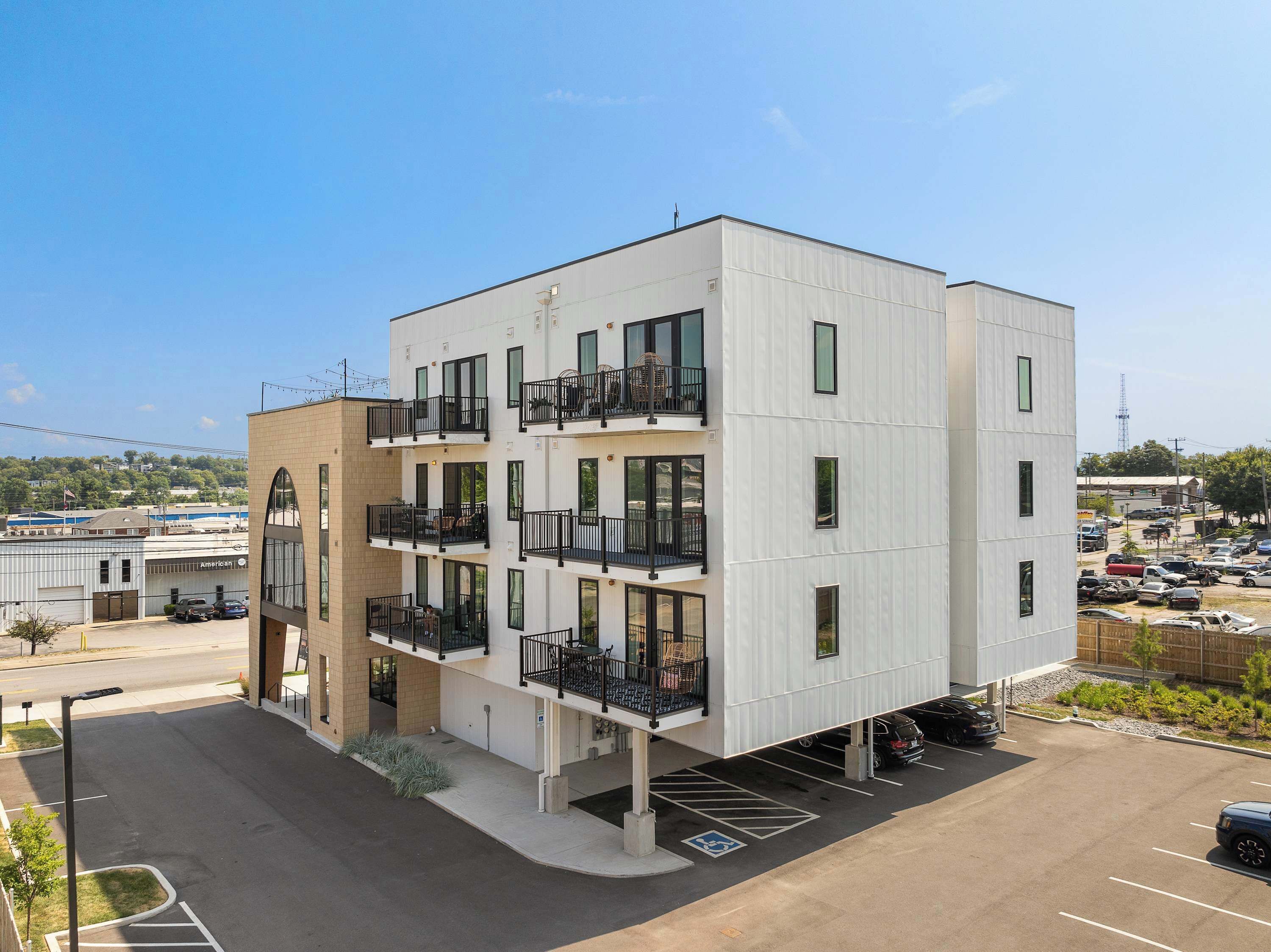 A multi-story building with balconies, a parking lot, and a clear sky.