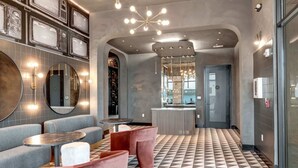 A modern lobby with grey sofas, a check-in counter, and a patterned floor. - Nashville Designer PH City Views + Rooftop Access (Nashville)