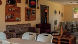 A room with a tiled floor, a ceiling fan, a wooden bench, a sofa, and a table with chairs. - Minerva Hotel and Restaurant (Playa San Blas)