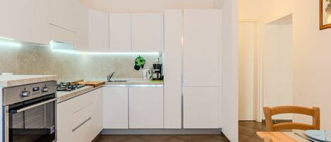 Een koelkast, een oven, een vaatwasser, kookgerei, borden en bestek