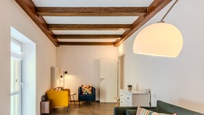 A modern living room with exposed wooden beams, a sofa with striped pillows, a yellow chair, and a lamp.