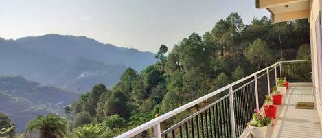 A balcony with a white railing overlooking a mountainous landscape.