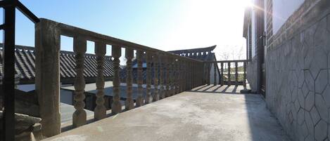 A corridor with a stone wall and a wooden railing.