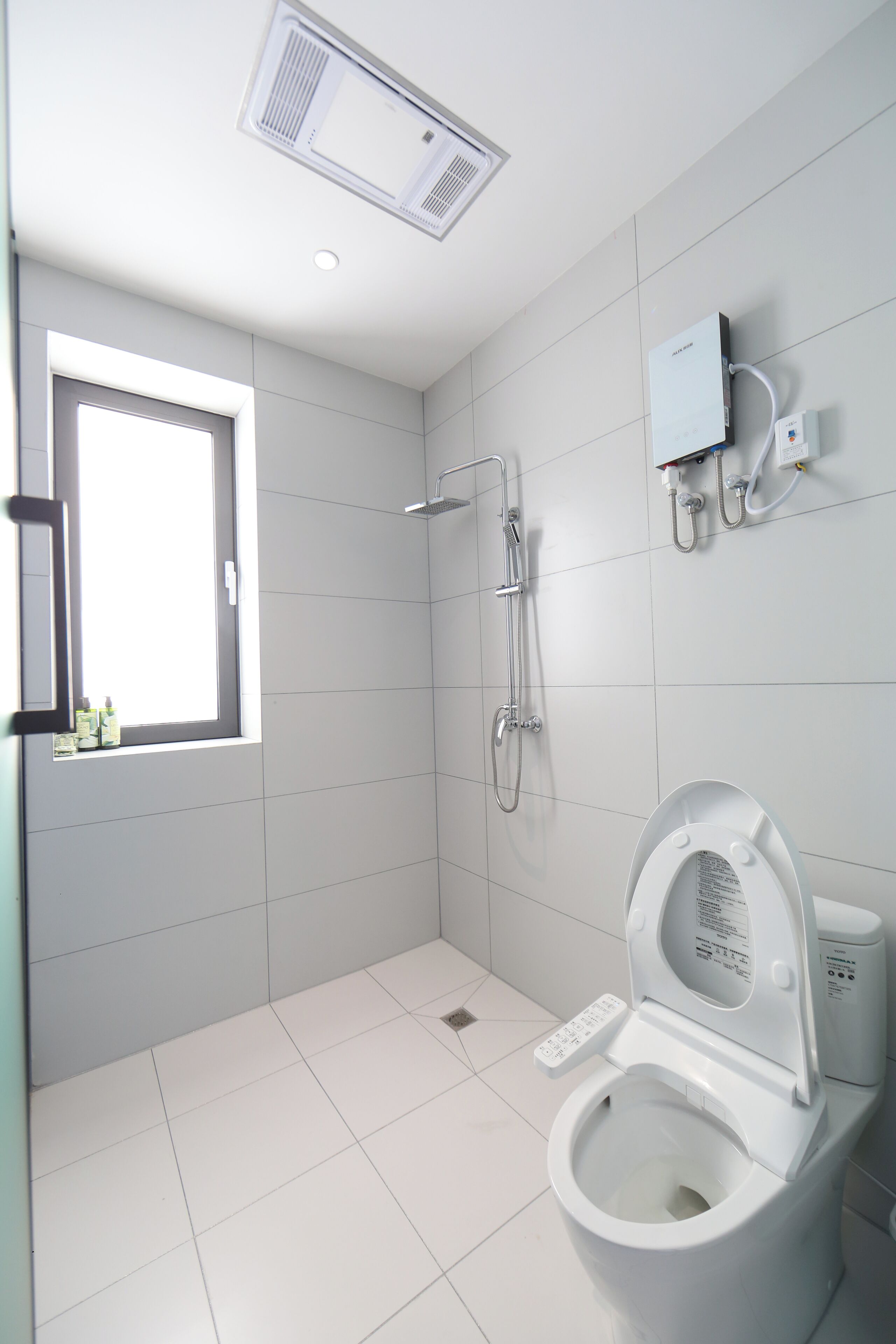 Une salle de bain moderne avec des toilettes, une douche et une fenêtre.