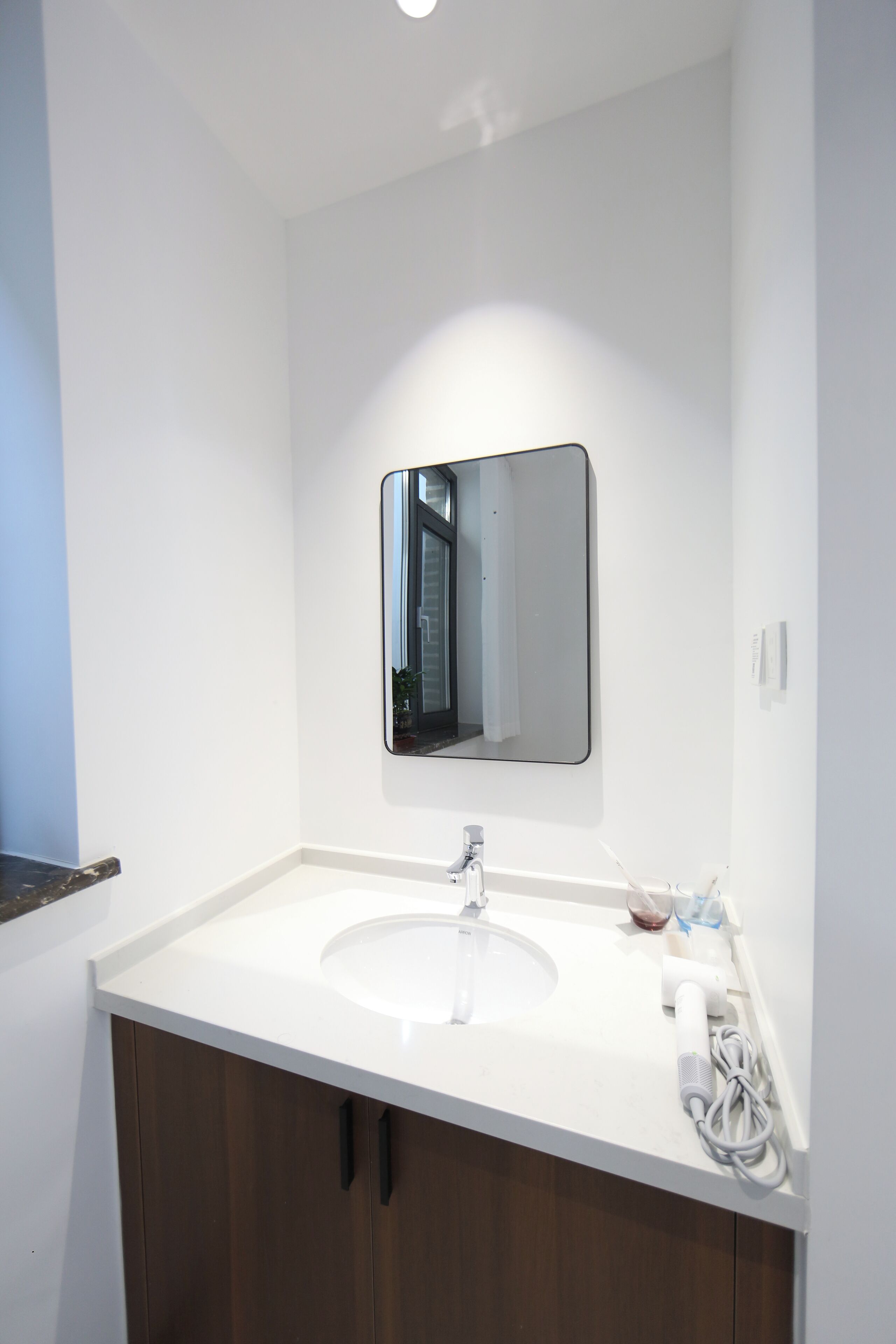 A modern bathroom with a white sink, dark wooden cabinets, and a mirror above the sink.